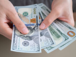 An individual counting through $100 bills