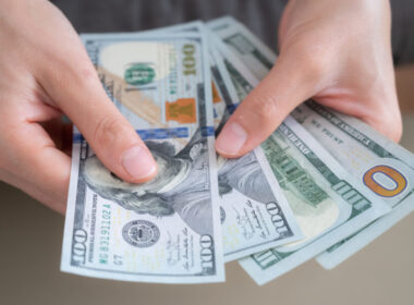An individual counting through $100 bills
