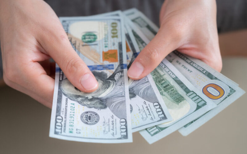 An individual counting through $100 bills