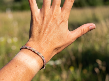 A woman's hand, tanned from the sun, with a tan line on her left wrist in place of a watch.